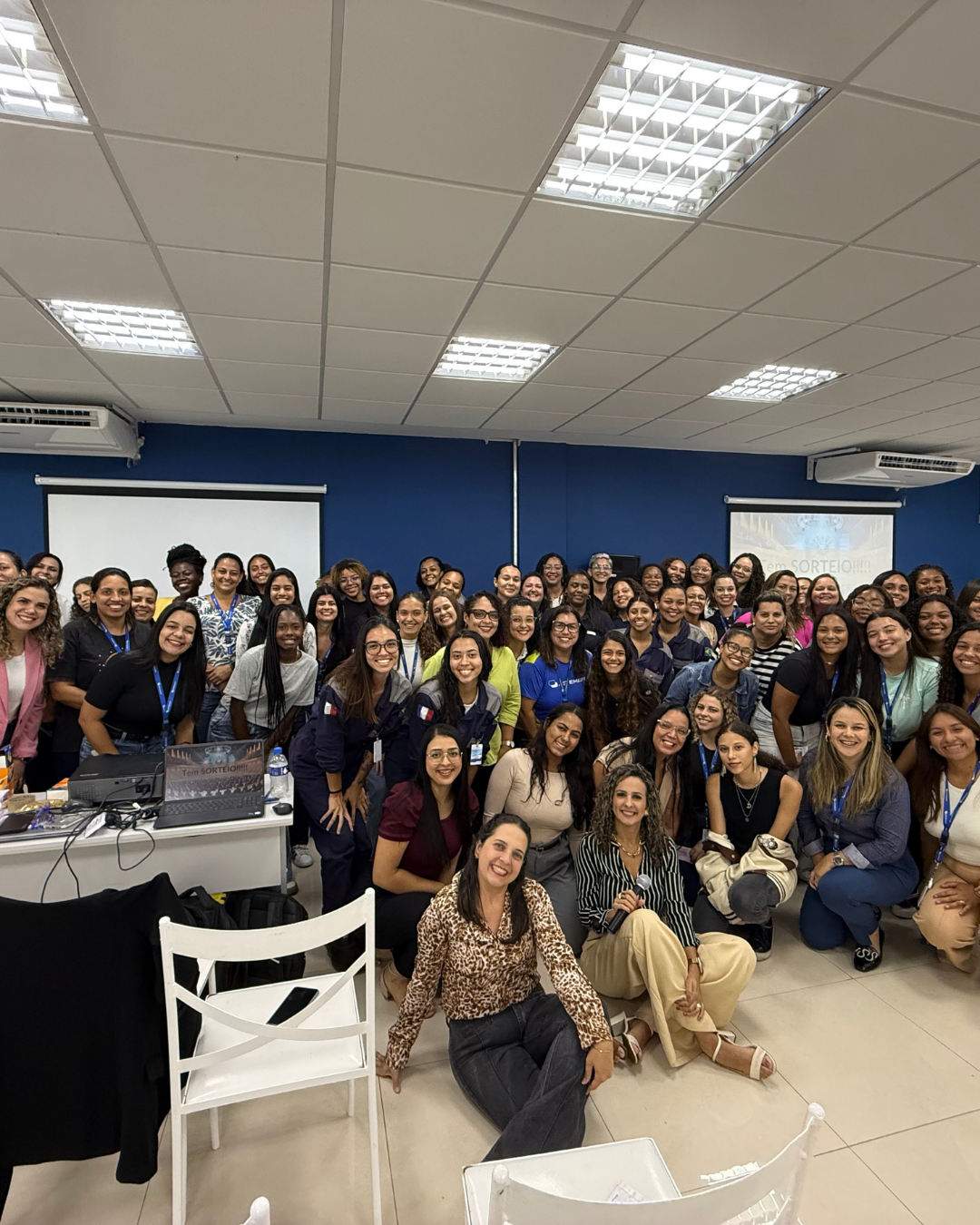 Turma numerosa reunida em sala de treinamento com Camila Couto