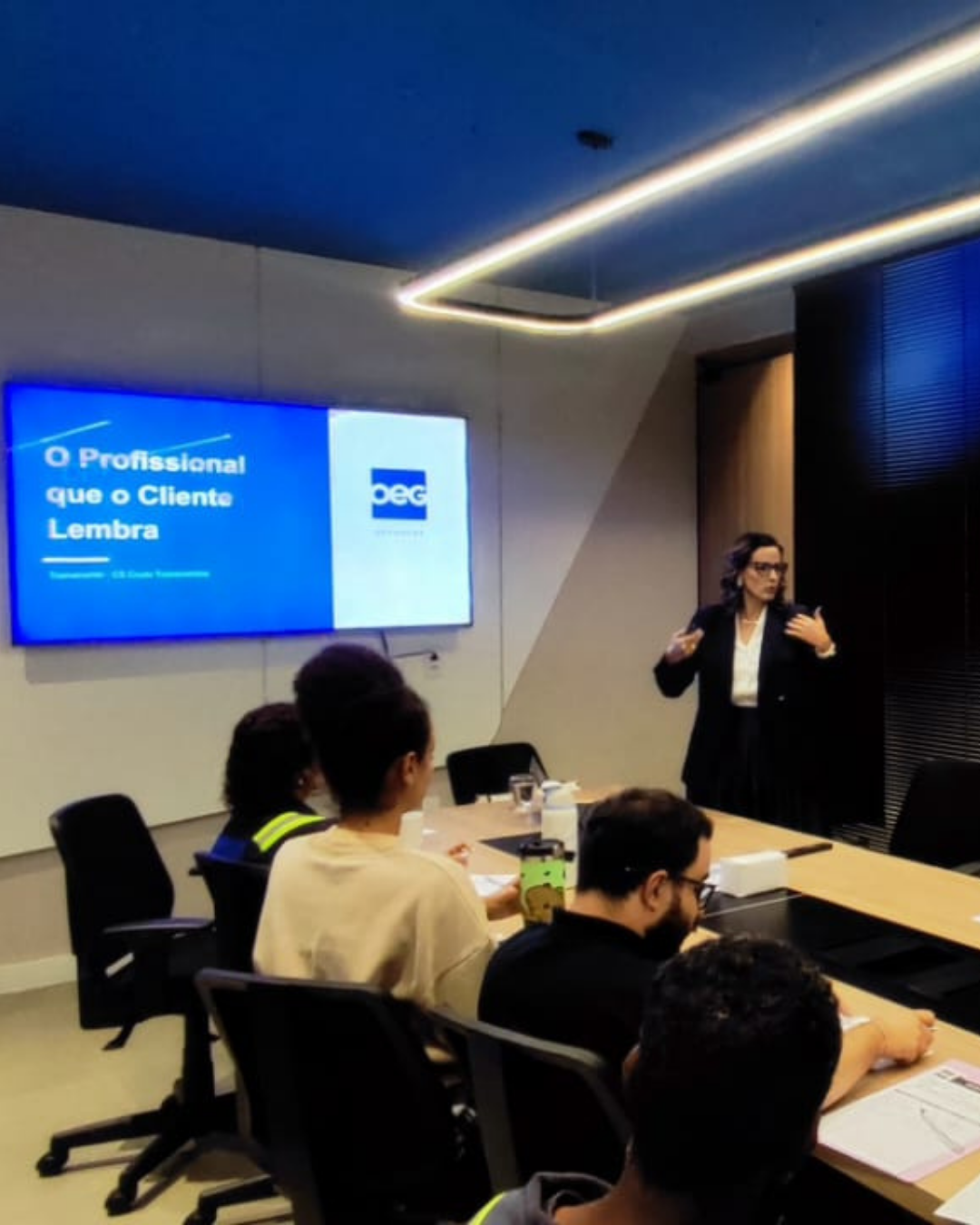 Camila Couto apresentando em sala de reunião corporativa